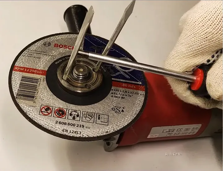 Using two screwdrivers crossed in flange holes to loosen nut